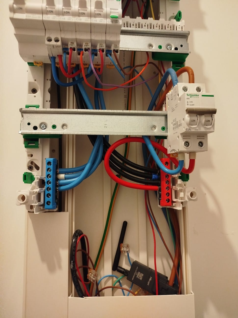 A wireless energy sensor installed inside a consumer unit alongside the breakers