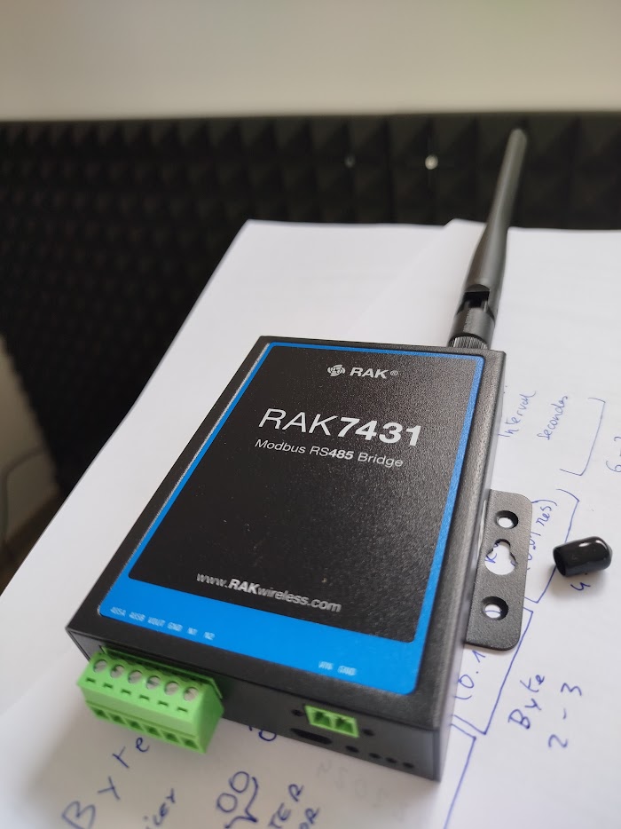A Modbus RS485 to wireless bridge on the bench beside handwritten payload mapping notes
